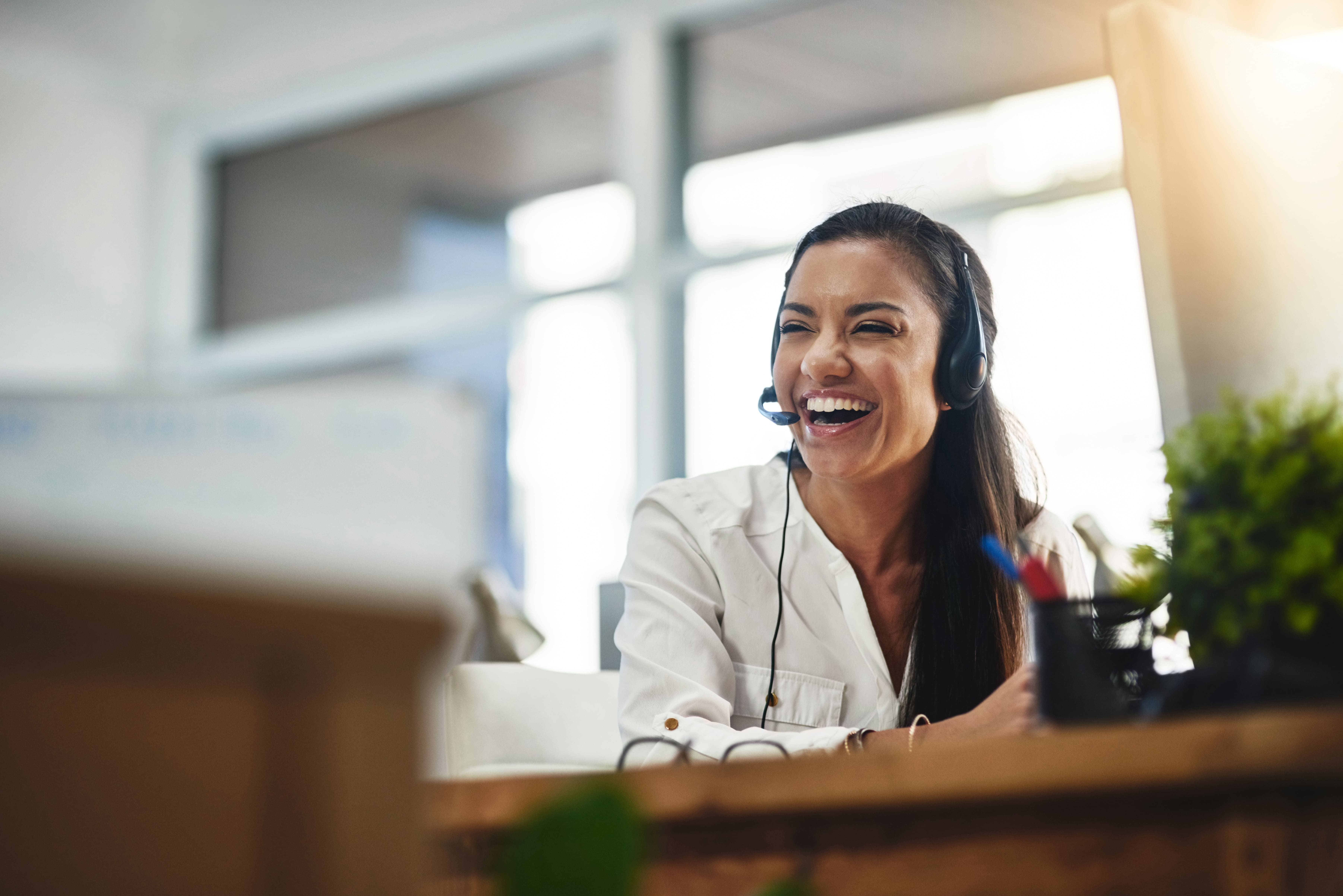 Kundenberaterin arbeitet mit KI-unterstütztem Headset im modernen Büro